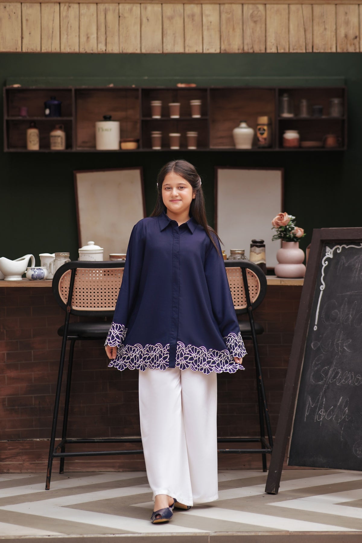 Lily navy blue button-down tunic with white floral embroidery on cuffs and scalloped hem worn by a young girl