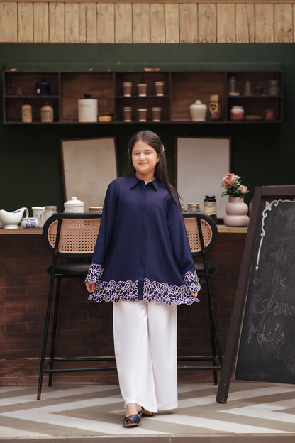 Lily navy blue button-down tunic with white floral embroidery on cuffs and scalloped hem worn by a young girl