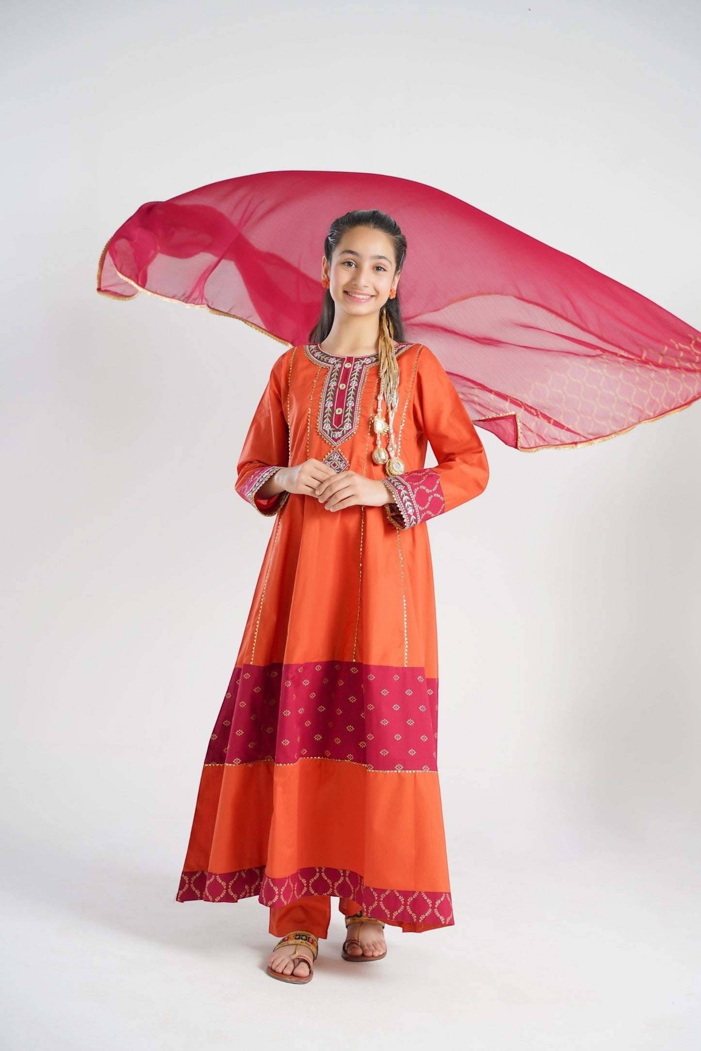 Lily orange embroidered kurta set for girls with pants and dupatta. Features gold print and maroon panels.