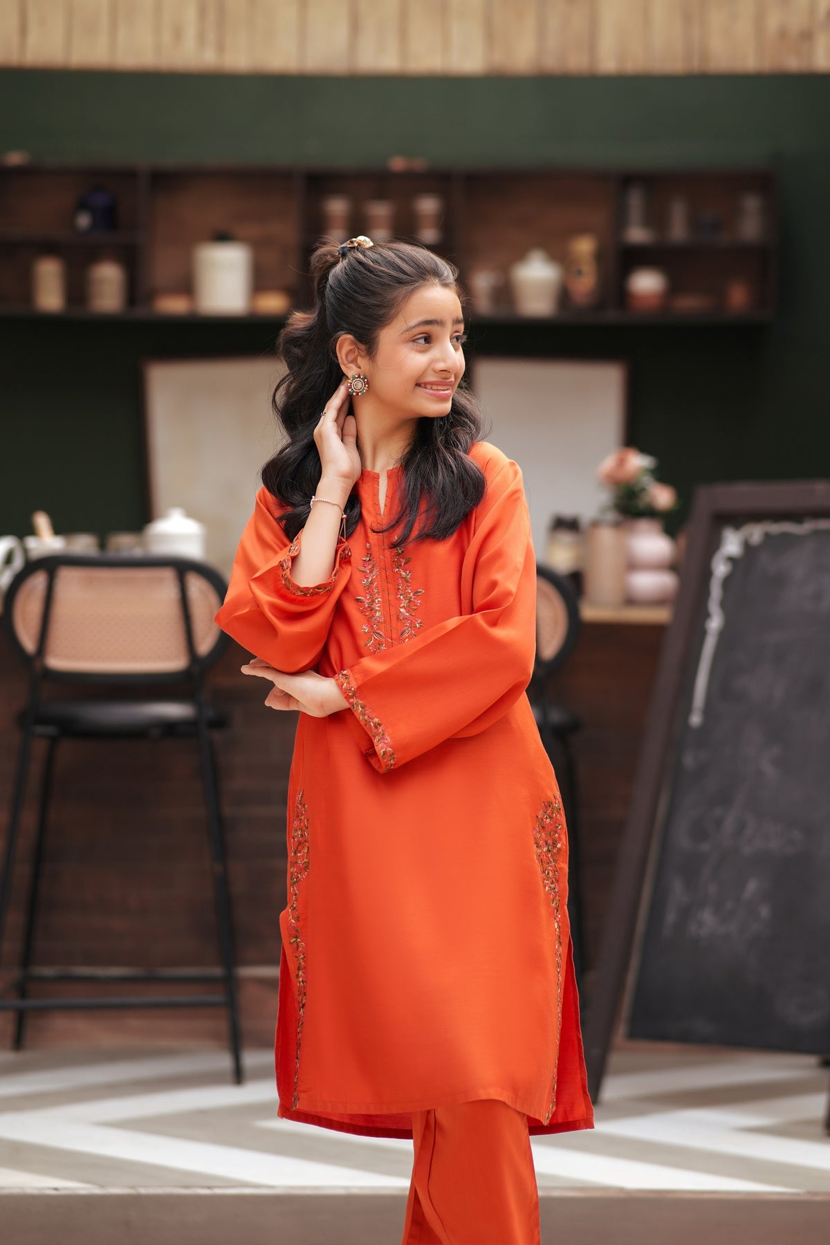 Lily orange kurta and trouser set with delicate floral embroidery on neckline and sleeves worn by a young girl