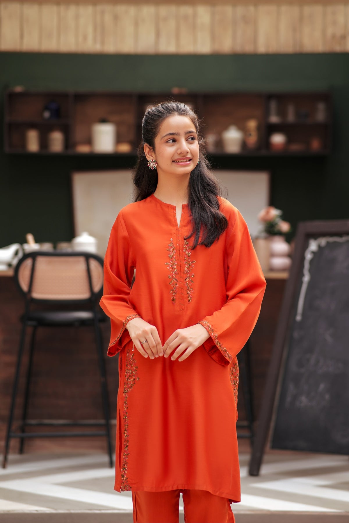 Lily orange kurta and trouser set with delicate floral embroidery on the neckline and sleeves worn by a young woman