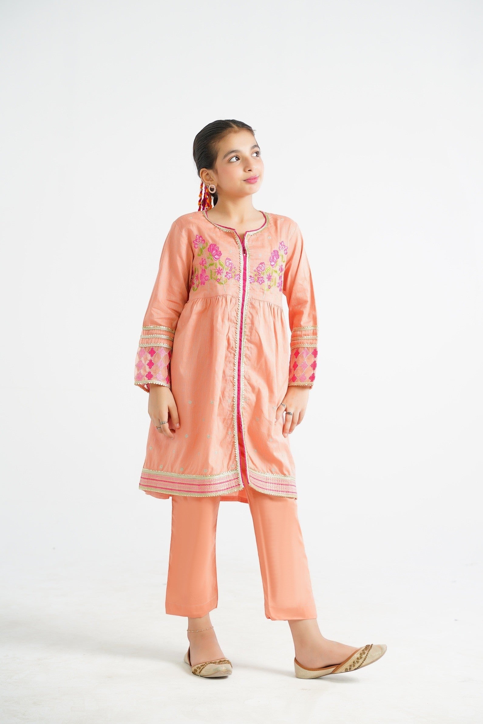 Lily peach embroidered kurta and pants set with floral motifs and border detailing. A young girl models the outfit.