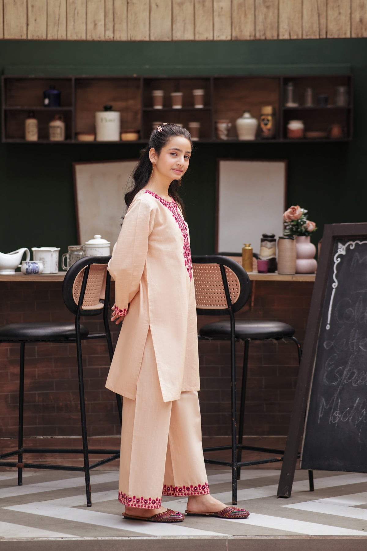 Lily girls peach kurta and trouser set with magenta floral embroidery and mirror work in a cafe setting