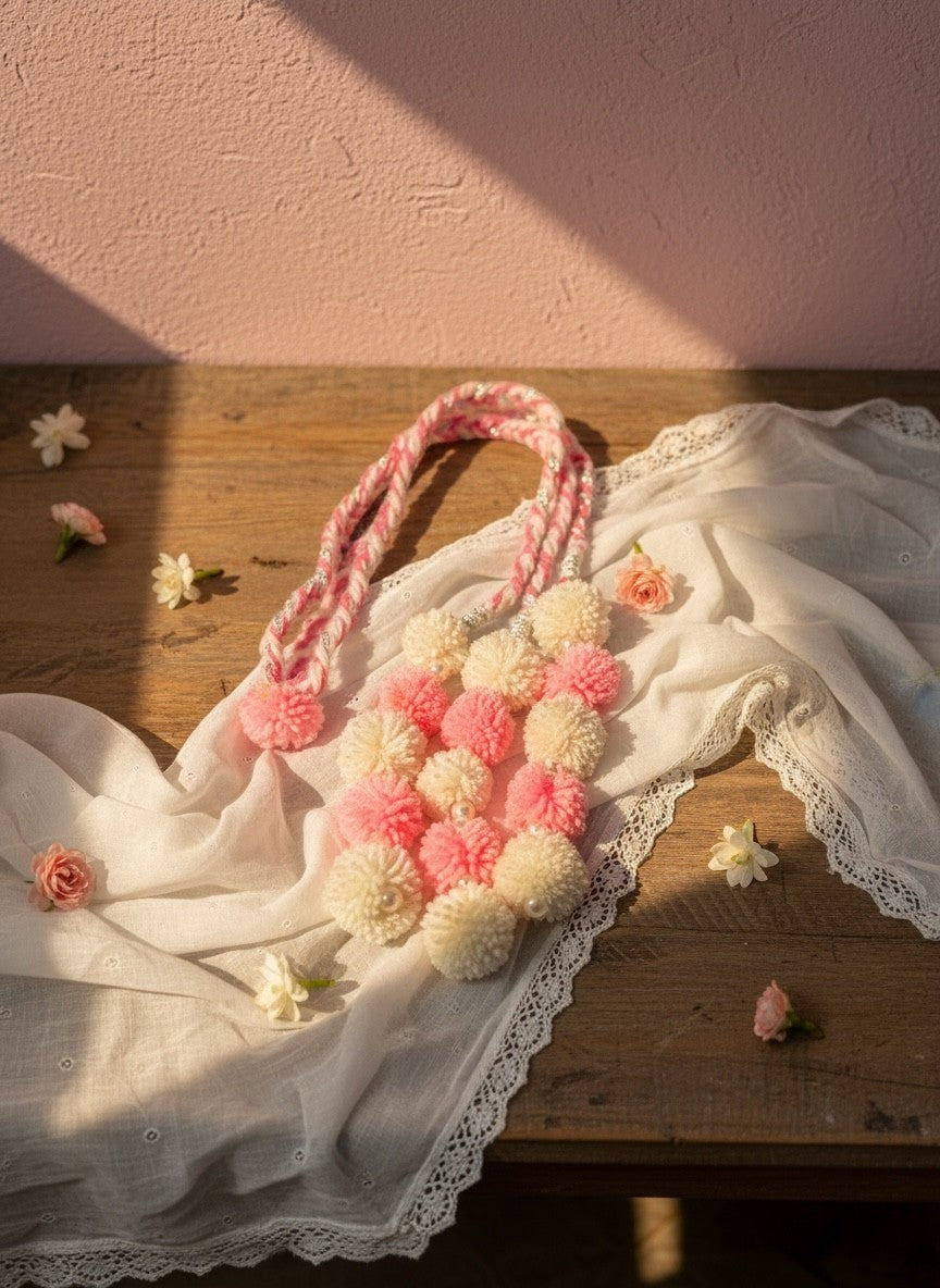 Lily pom pom tassel hair accessory in pink and cream with pearl accents and braided cord, perfect for adding playful elegance.