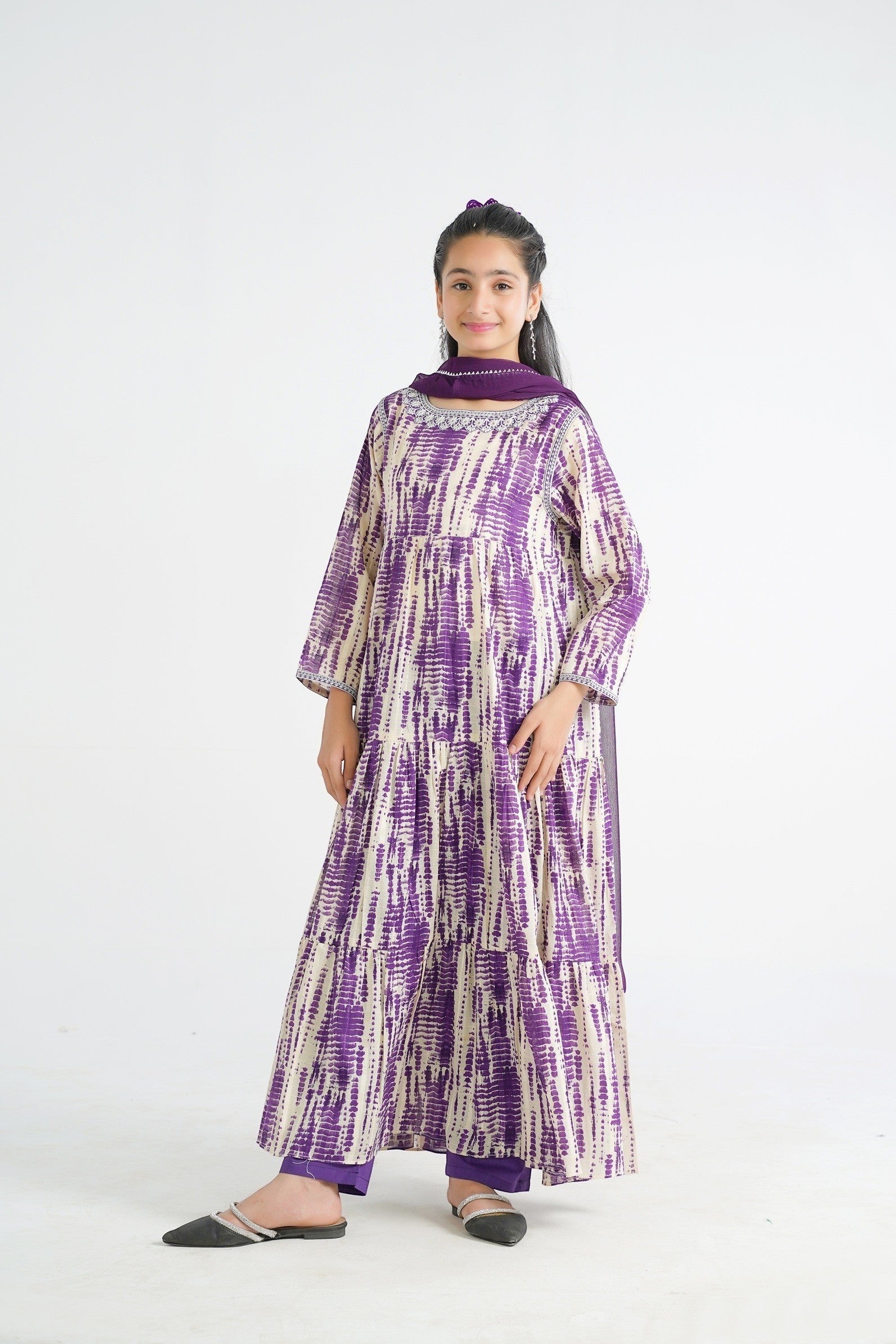 Lily tiered maxi dress in purple and cream tie-dye print with embroidered neckline and matching scarf. Model wears purple trousers and embellished flats.