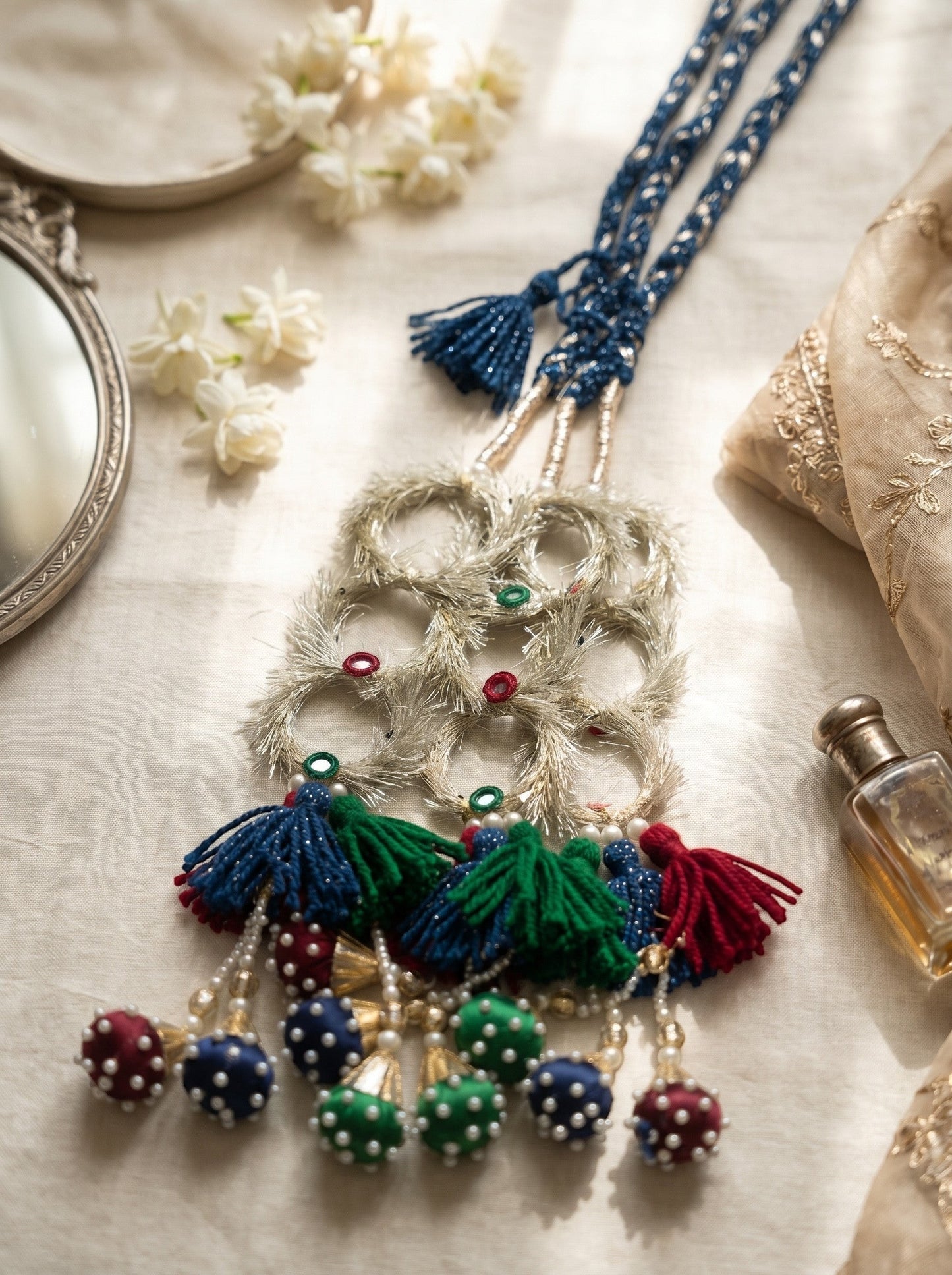 Lily Ruby Heer Paranda featuring a blue braided cord, silver mirror-work accents, and colorful tassels with pearl pom-poms.