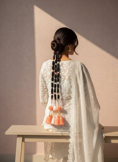 Lily handcrafted coral, white, and black tassel hair accessory with pom-poms and gold beads woven into a braid.