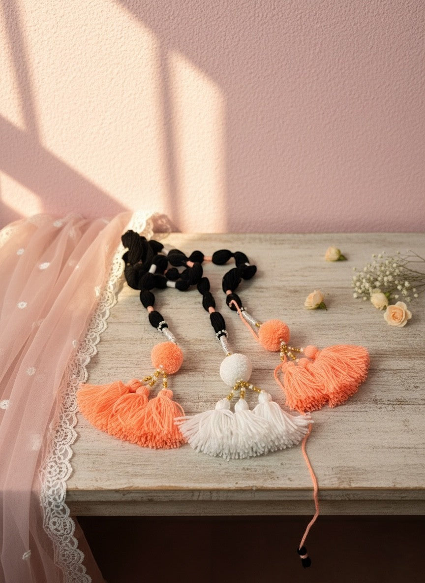 Lily handcrafted coral, white, and black yarn hair accessory with pom-poms and gold beads.