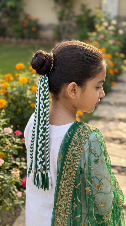 Lily Watan Love braided hair accessory with green and white yarn strands and metallic charms worn in a high bun