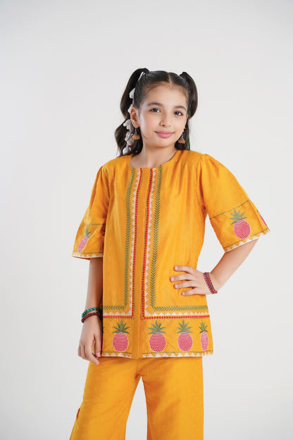 Lily yellow textured cotton kurta and pants set with pineapple embroidery and green/red trim. Girl model.