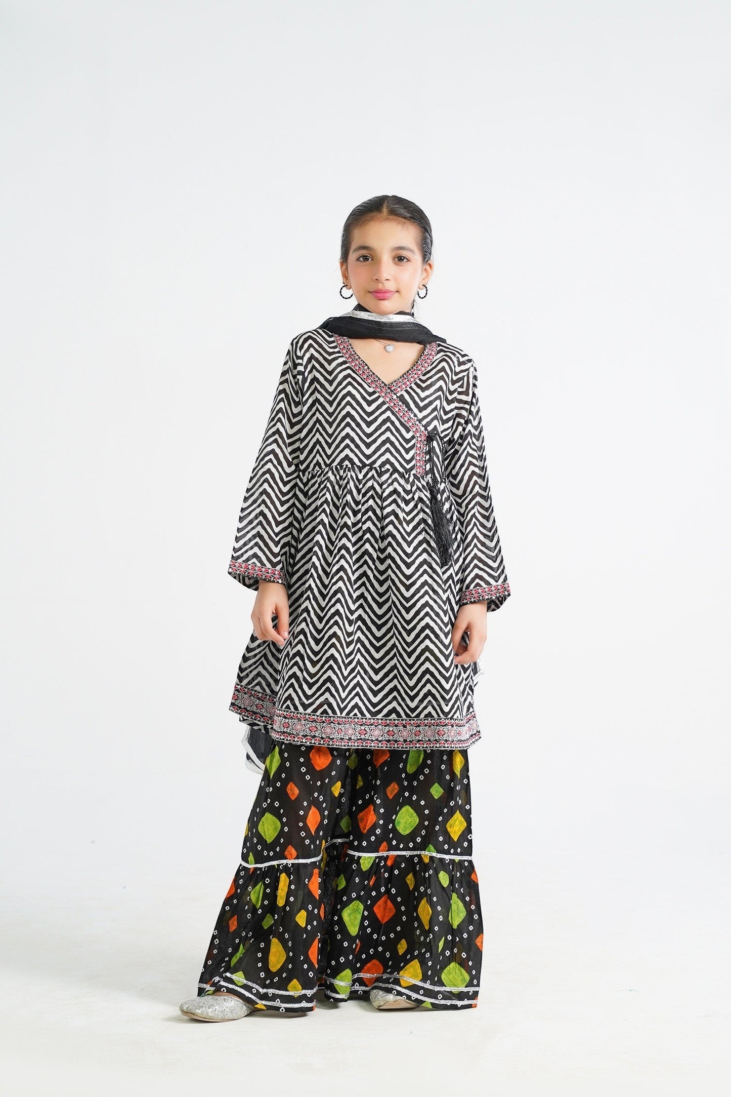 Lily black and white zigzag print kurta with red embroidery and tassels, paired with colorful tiered sharara and dupatta.